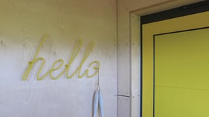 vibrant yellow welcome home sign next to bright front door on a project in Chapel Port, Cornwall