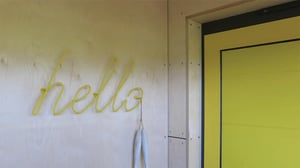Welcoming entrance with yellow door and hello sign