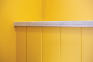 close up of bright yellow wall with ply shelf