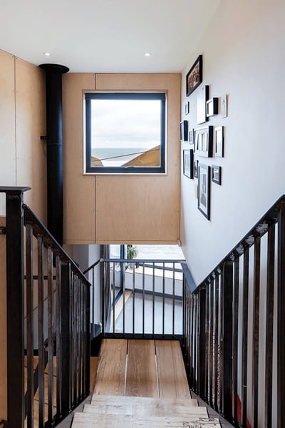 view from top off a staircase looking out of a window towards the beach