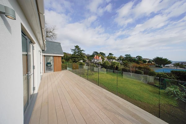 first floor balcony with glass guarding looking out over mature garden