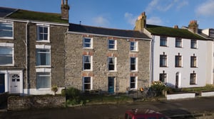 stone terrace house with eight white windows and blue central door