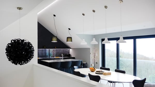 monochrome kitchen and dining area with large black steam bent wood light fitting