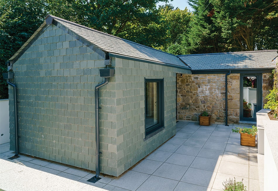 contemporary natural hung slate rear extension clad set against traditional stone outbuilding