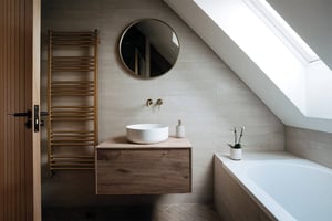 bathroom with circular mirror, washbasin and gold towel rail
