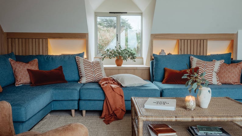 large blue sofa with burnt orange accent cushions