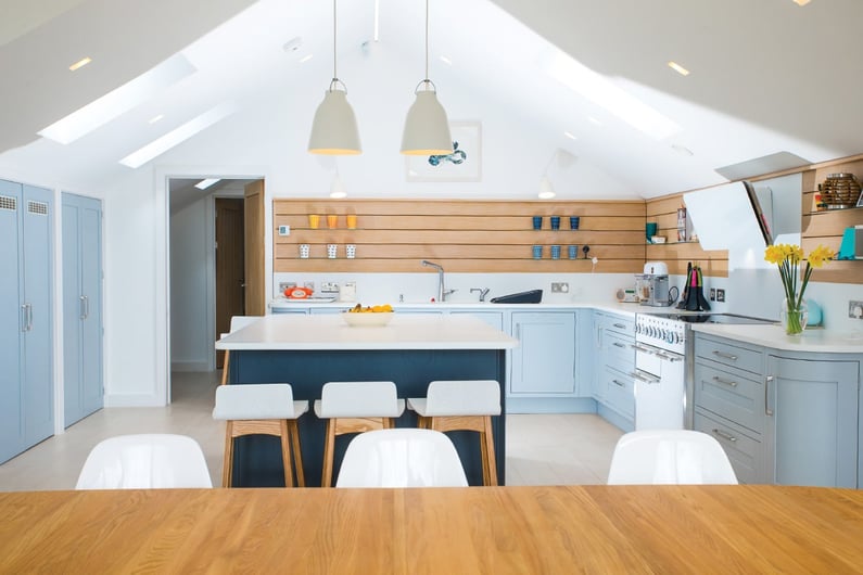 pale blue kitchen with white worktop and horizontal wood on walls