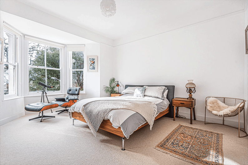 master bedroom with Eames chair in large bay window